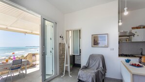 A room with a balcony overlooking the sea, a kitchenette, and a covered seating area. - La Casa in Riva al Mare (Santa Croce Camerina)