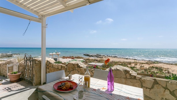 A seaside patio with a table set for two, overlooking the beach and ocean. - La Casa in Riva al Mare (Santa Croce Camerina)
