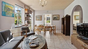 Ein Wohnzimmer mit Essbereich, Fernseher und Bücherregal.