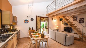 Una cucina moderna con zona pranzo, divano e scala.