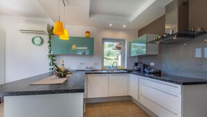 A modern kitchen with white cabinets, a black marble countertop, and a window providing a view of greenery outside.