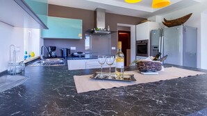 A modern kitchen with a marble countertop, a wine bottle, and two glasses on a tray.