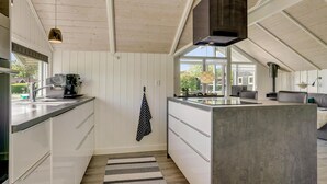 Cozinha moderna com ilha central, teto de madeira e uma grande janela que proporciona luz natural.
