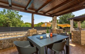Enjoy a patio with a table for four, surrounded by a stone wall and offering a view of the surrounding area.