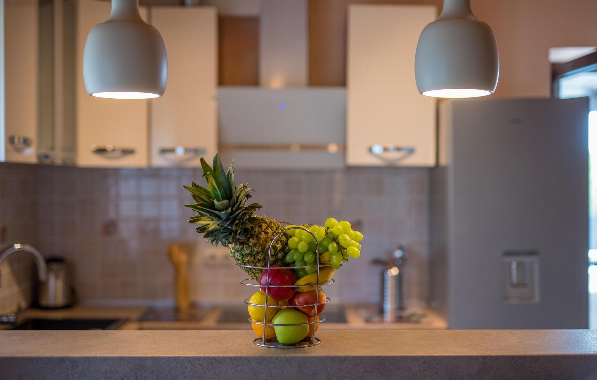 Eine Küche mit Obstschale, die Ananas, Trauben und Äpfel auf der Arbeitsfläche enthält.