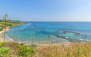 Un paisaje costero con aguas turquesas cristalinas, una playa de arena y embarcaciones fonqueadas cerca de la orilla.