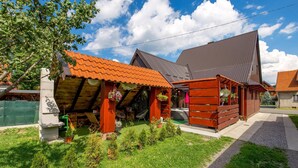 A wooden cabin with a red-tiled roof, a small porch, and a garden area with potted plants. - Beautiful home in Mrkopalj with sauna (Mrkopalj)