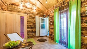 A wooden cabin interior with a wooden door, a table with a fruit bowl and glasses, and a green rug. - Beautiful home in Mrkopalj with sauna (Mrkopalj)