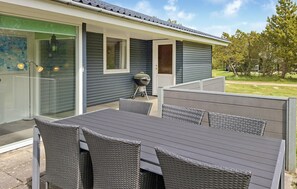 An outdoor patio with a table and chairs, a grill, and a sliding glass door leading to a covered area. - 3 bedroom gorgeous home in Blåvand (Blåvand)