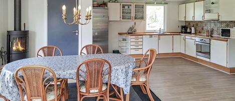 Een gezellige keuken met een centraal eiland, een inbouwfornuis en rieten stoelen rond een tafel.