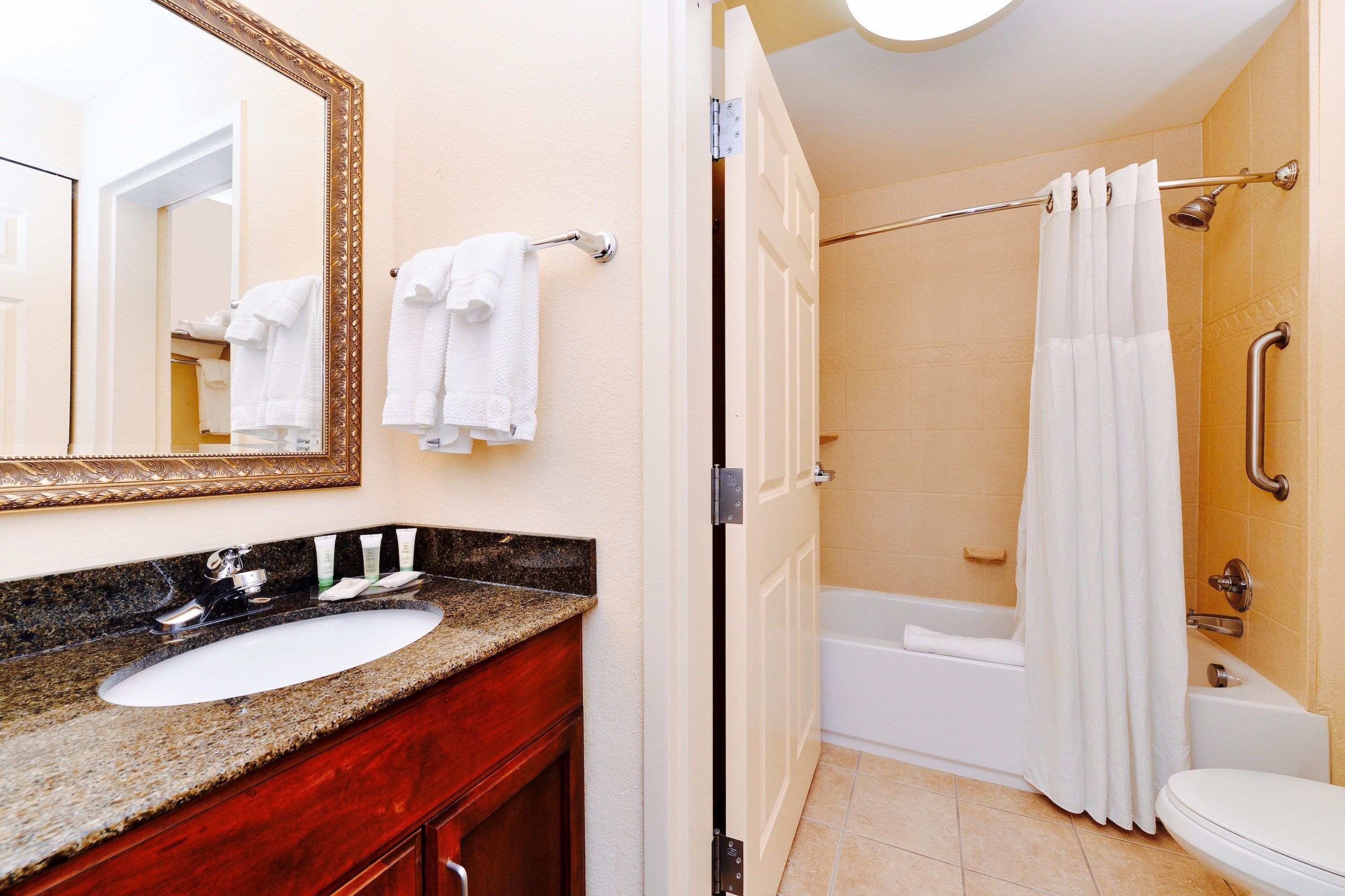 A bathroom with a sink, mirror, and a shower area with a curtain.