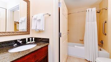 A bathroom with a sink, mirror, and a shower area with a curtain.