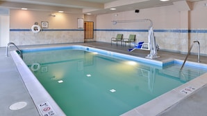 An indoor swimming pool with a tiled wall, a lifeguard chair, and a pool ladder. - King Suite | Shared Indoor Pool + Free Breakfast (Stafford)