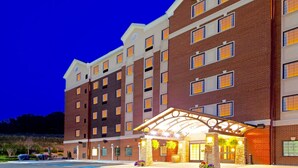 A multi-story hotel with a brick facade, a covered entrance, and a sign indicating Staybridge Suites.