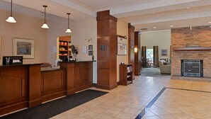 A reception area with a wooden desk, pendant lighting, a fireplace, and a seating area with a couch and chairs.