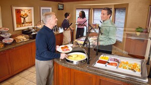 A buffet area with various food items and a counter where staff are serving guests.