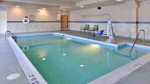 An indoor swimming pool with a tiled wall, a lifeguard chair, and a pool ladder.