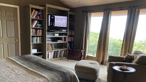 A bedroom with a large bed, a sofa, a television, and a bookshelf. - Beautiful Mountain Vacation Rental (Pipe Creek)
