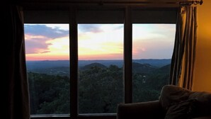 A room with a large window offering a view of a mountainous landscape at sunset. - Beautiful Mountain Vacation Rental (Pipe Creek)