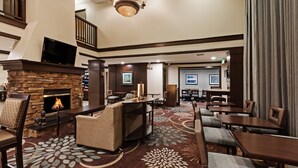 Een hotel lobby met een open haard, zithoek en een trap.