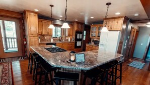 A kitchen with a large island, wooden cabinets, and a stainless steel refrigerator.