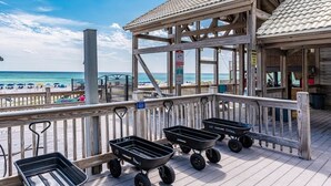 Eine Holzterrasse mit Blick auf den Strand, ein überdachter Sitzbereich und Schubkarren mit der Aufschrift 'Topaz'.