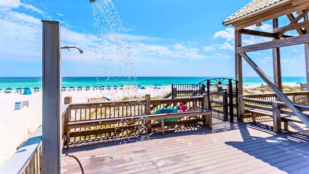 Eine Holzterrasse mit Blick auf Strand und Meer.