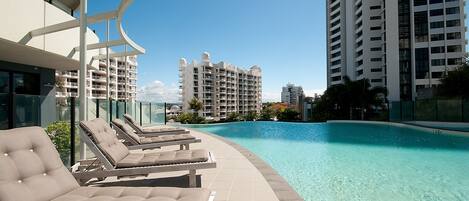 A poolside area with lounge chairs and a clear view of high-rise buildings in the background.