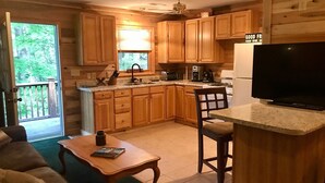 Una cocina acogedora con armarios de madera, un comedor con mesa y sillas, y un televisor sobre una encimera.