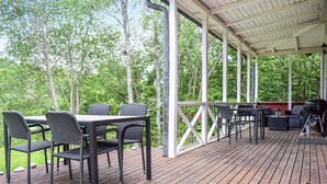 Eine Terrass mit überdachtem Sitzbereich, inklusive Tisch, Stühlen und Grill.
