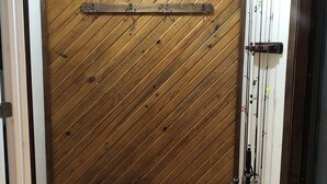 A room with a wooden wall, a bench, and fishing rods.