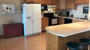 A kitchen with wooden cabinets, a white refrigerator, a microwave, and a coffee maker. - Amazing Fall Colors, Nature, Fireplaces, Screened Porch, Secluded! (Hayward)