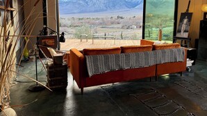 Un salon moderne doté d’une grande fenêtre donnant sur les montagnes, d’un canapé rouge et d’un décor de style rustique.