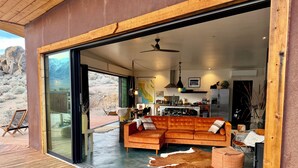 Un intérieur moderne avec une grande terrasse en bois, un canapé en cuir et un tapis en peau de vache.