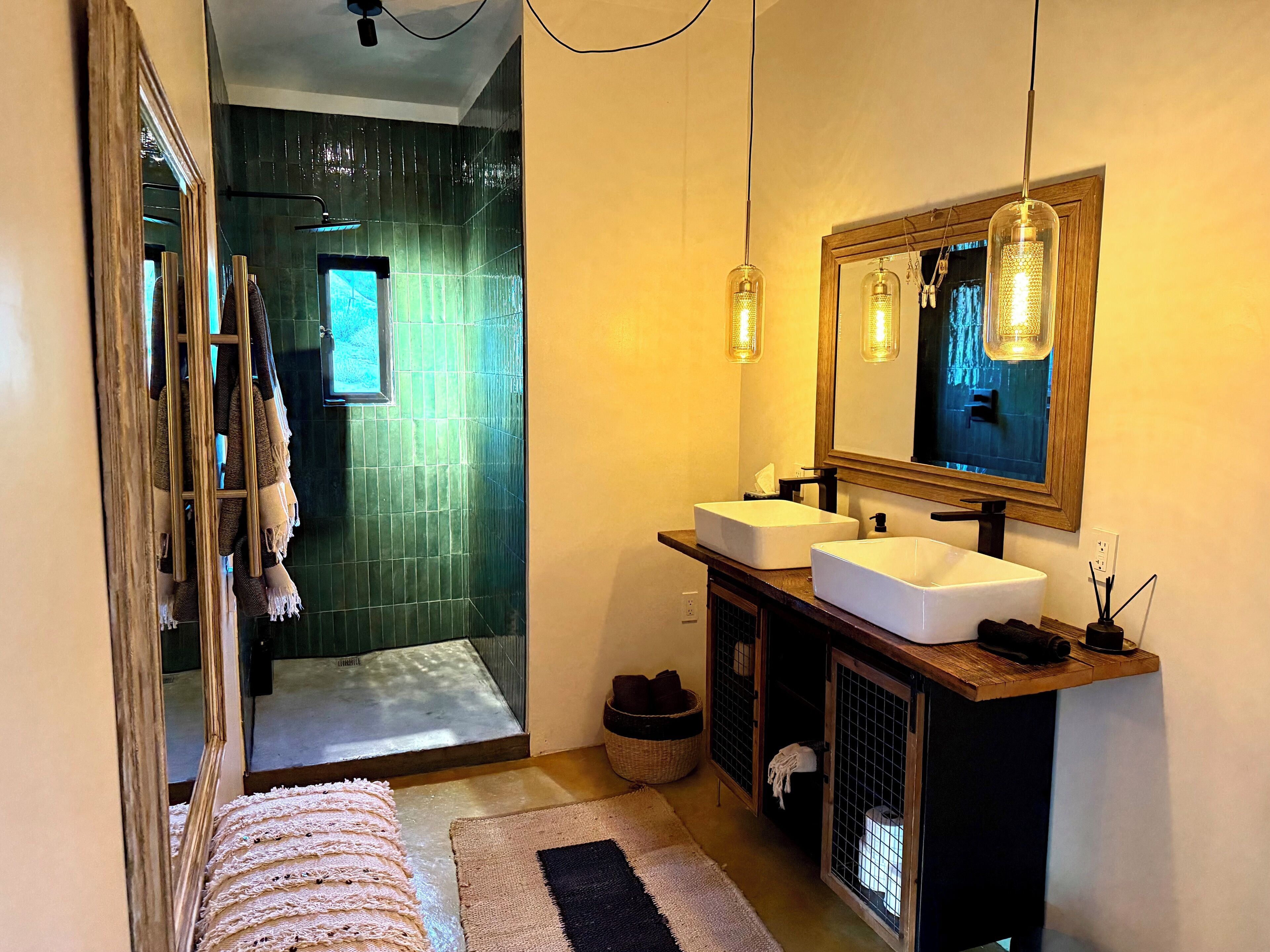 A modern bathroom with two sinks, a large mirror, and a shower area.