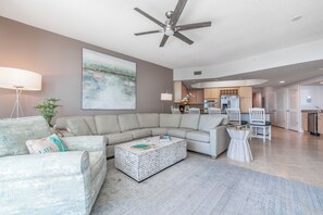 Un salon moderne avec un canapé d’angle, une table basse et un ventilateur de plafond.