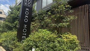 Ein Schild mit dem Schriftzug "KOKO HOTEL" und einem dahinterliegenden, vertikalen Holzzaun.