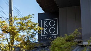 Ein Hotel-Schild mit der Aufschrift 'KOKO HOTEL' vor einer modernen Gebäudefassade.