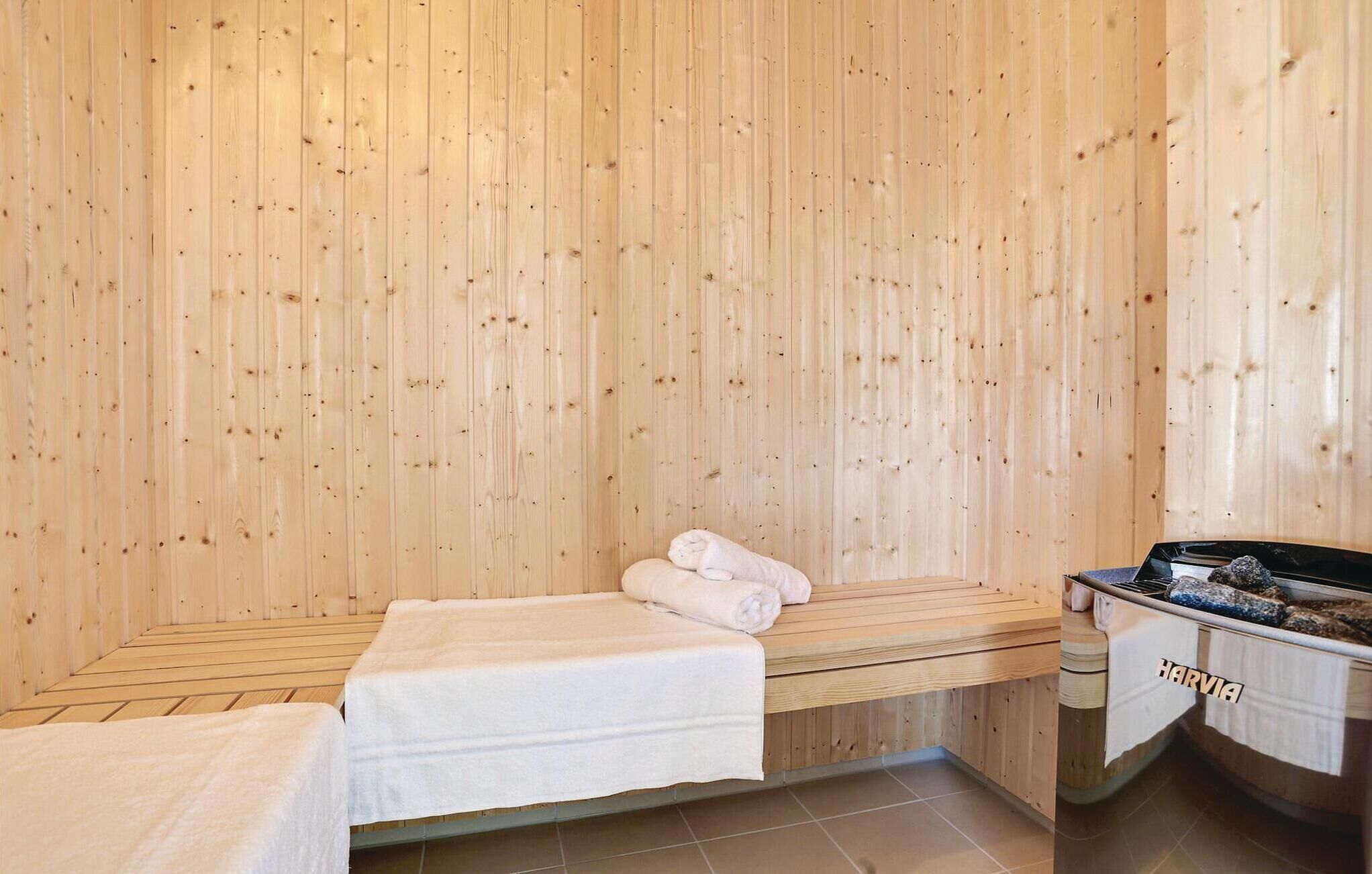 Un cuarto de sauna con paredes, bancos y una tina de madera.