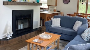 A spacious living room with a fireplace, a blue sofa, a wooden coffee table, and a nautical-themed rug. - Beautiful Broadkill Beach home with a short walk to the beach. (Milton)