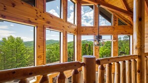A wooden cabin with large windows offering a view of green hills. - Luxury cabin w/indoor pool, hot tub, view, game rm (Sevierville)