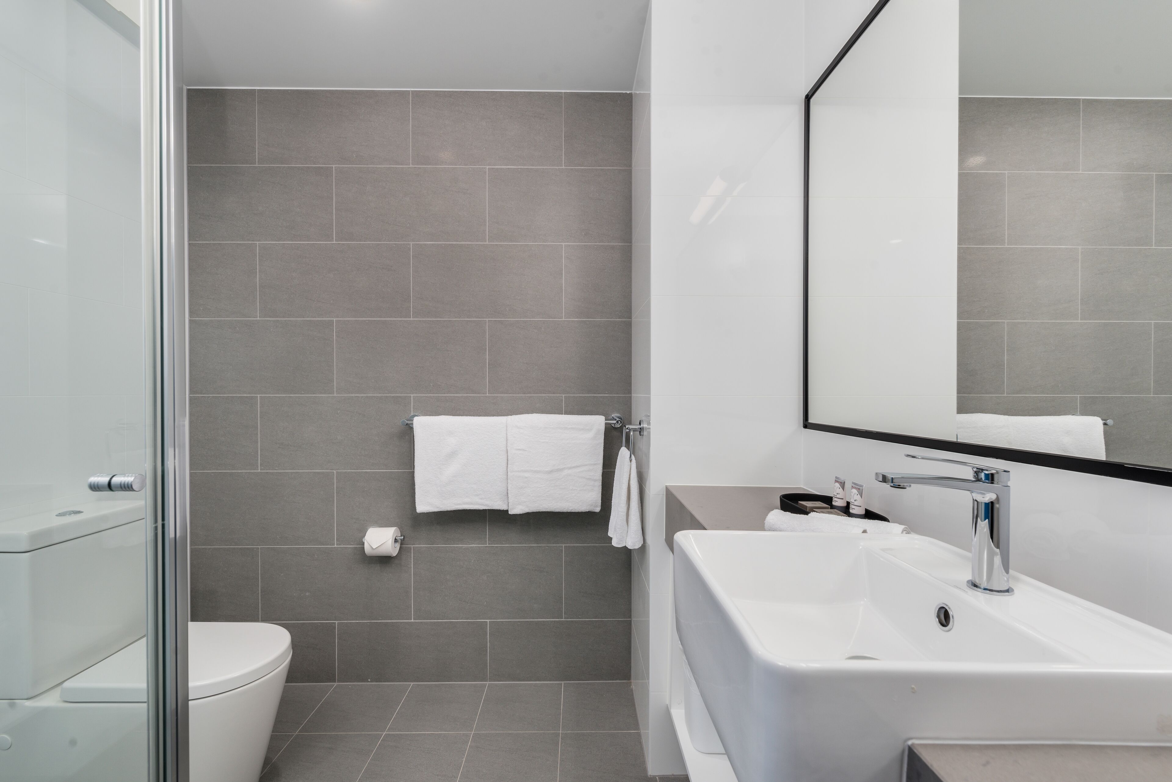 A modern bathroom with a toilet, sink, and shower area.