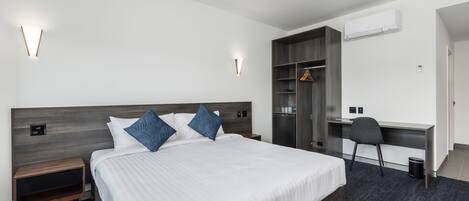 Una habitación de hotel moderna con una cama grande, mesitas de noche, un escritorio y un armario.