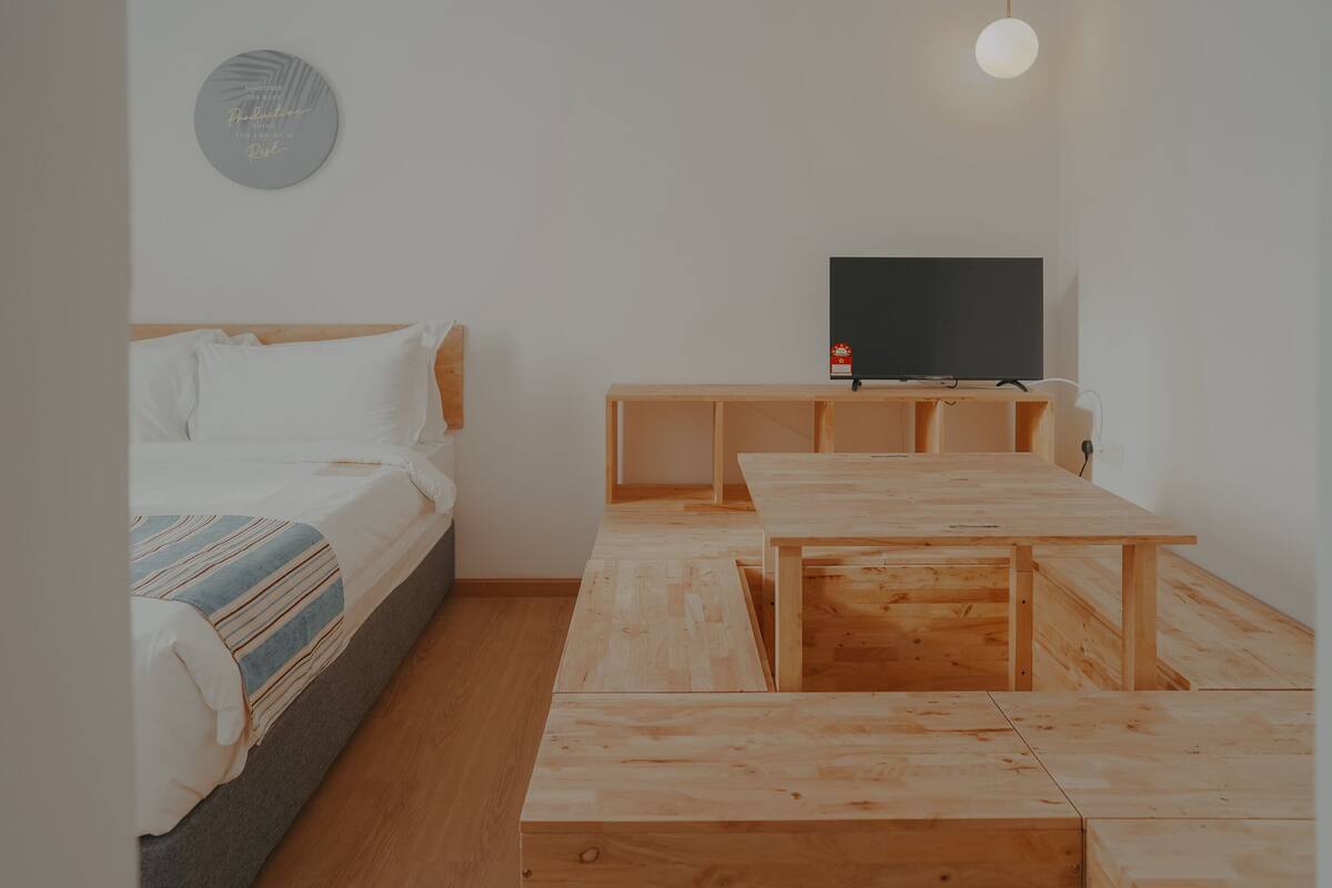 Een slaapkamer met een bed, een televisie en een houten tafel.