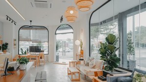 Un intérieur moderne comprenant un comptoir d’accueil, un espace salon, de grandes fenêtres et des plantes d’intérieur.