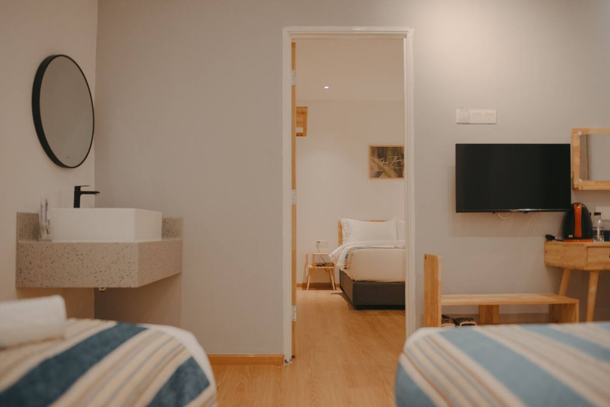 Hotelkamer met een bed, een televisie, nachtkastje, spiegel en een badkamer met wastafel en spiegel.
