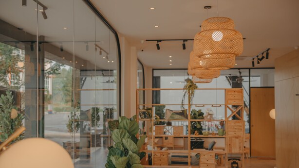 Un intérieur moderne avec des murs en verre, une étagère en bois et un luminaire suspendu.
