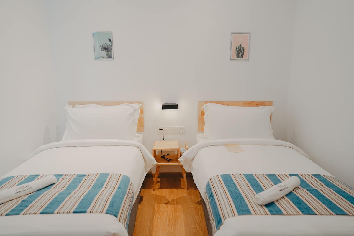 Een kamer met twee eenpersoonsbedden, een nachtkastje en een wandlamp.