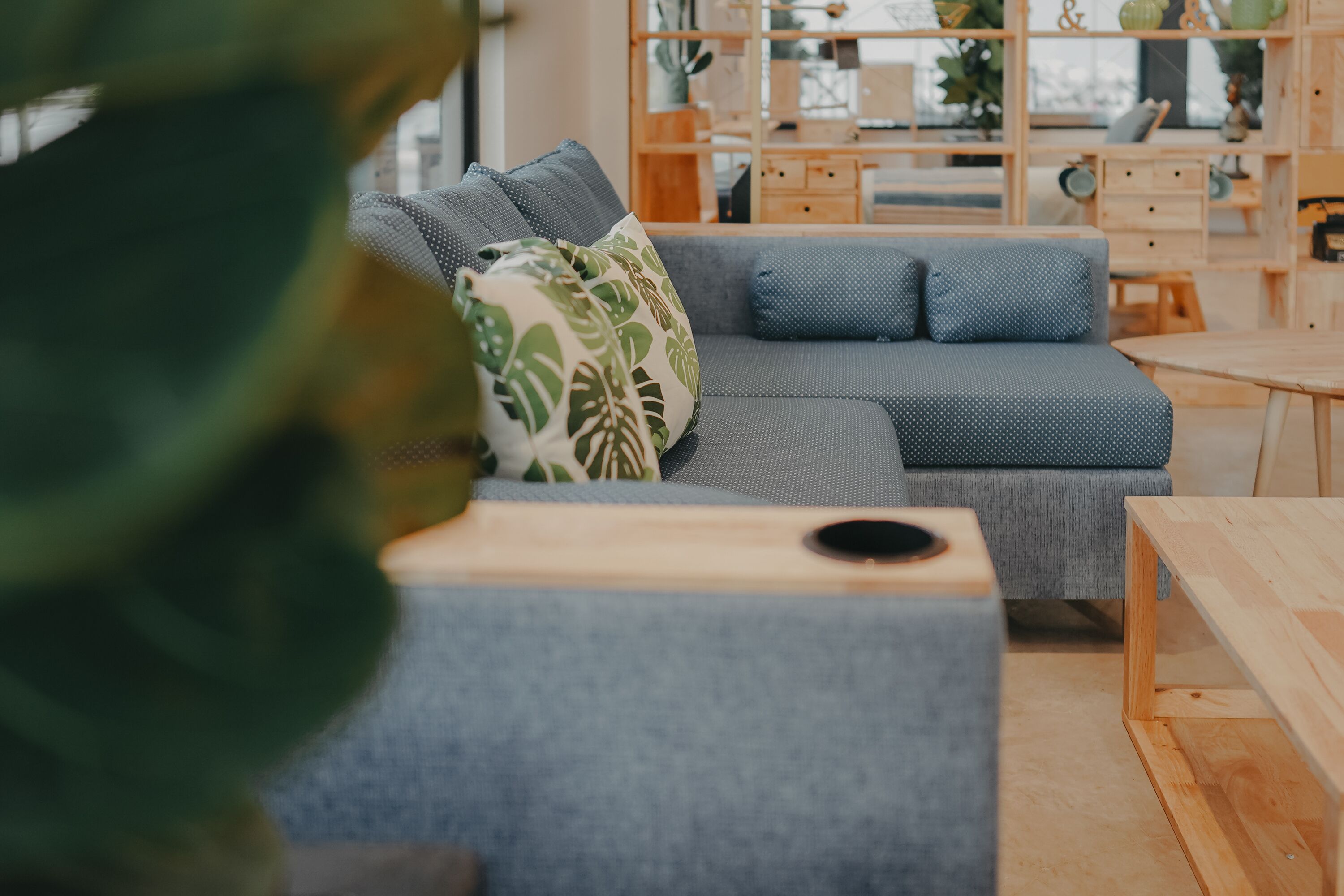 A modern living room with a grey sectional sofa, wooden coffee table, and a bookshelf in the background.