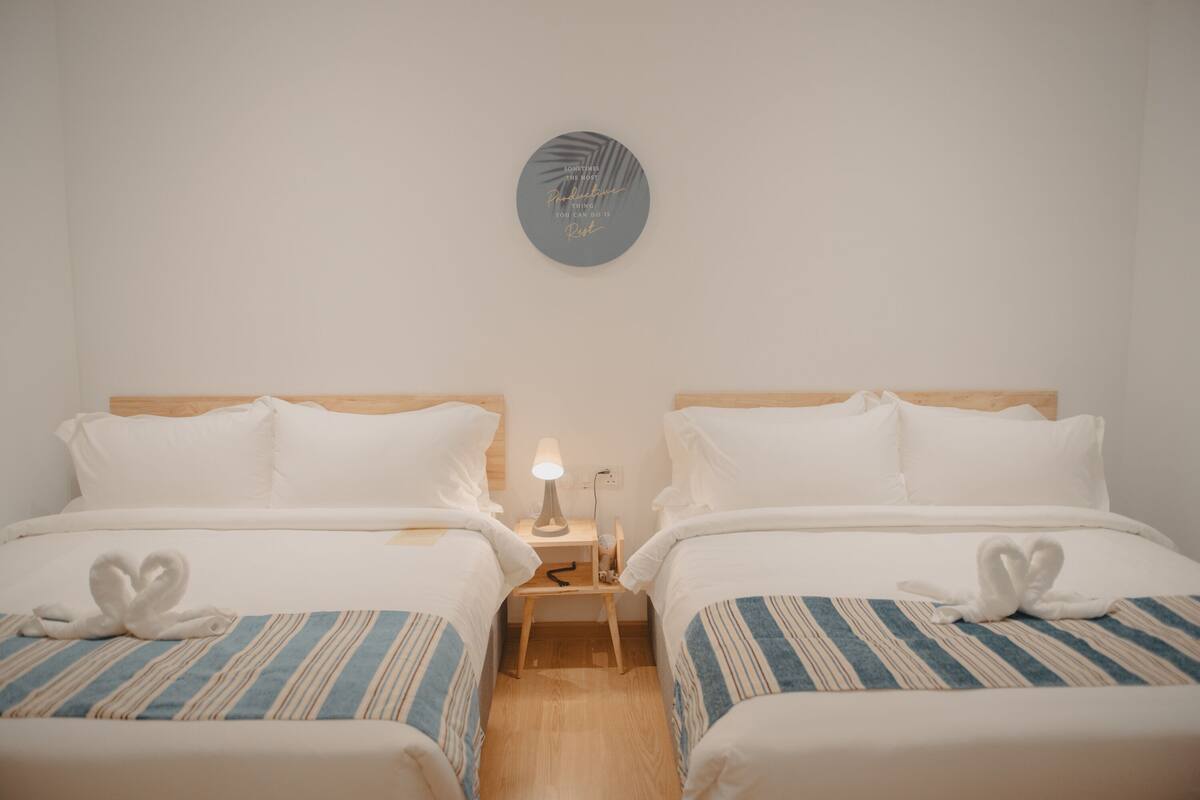Een hotelkamer met twee bedden, een nachtkastje met een lamp en een decoratie aan de muur.